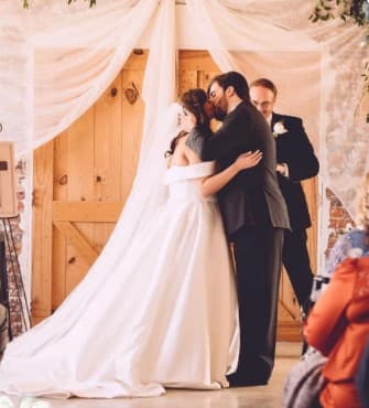 Couple sharing their first kiss under a draped arch