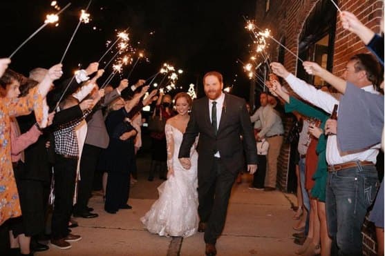 Couple walking out through a tunnel of sparklers at night