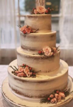 Four-tier naked cake with pink roses by a window